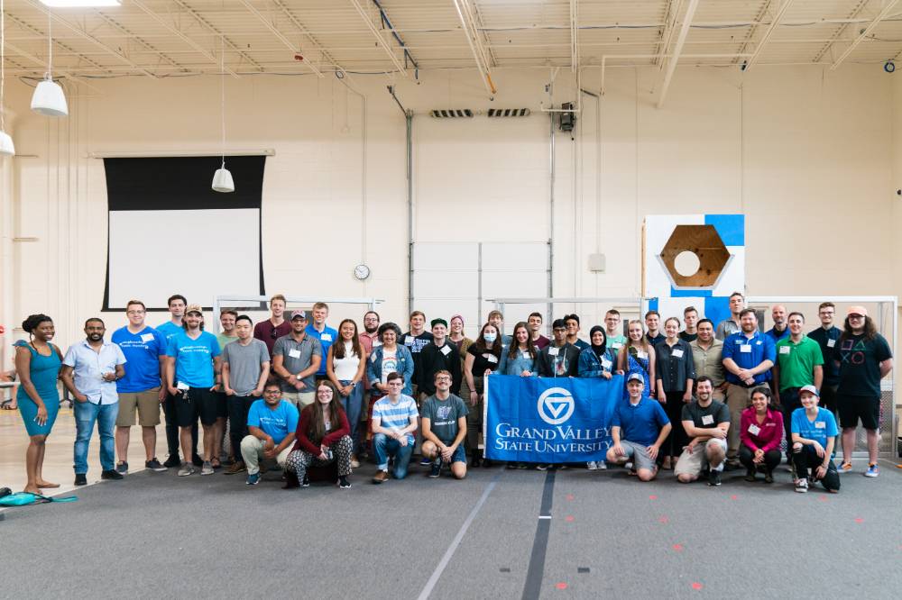Engineering students, faculty, and staff pose with the GVSU flag